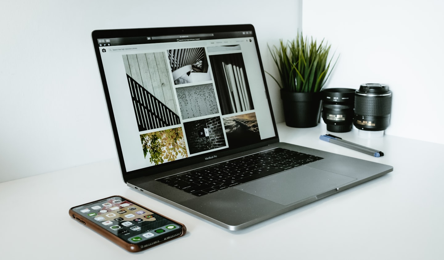Laptop na białym biurku z otwartą stroną internetową galerii zdjęć.